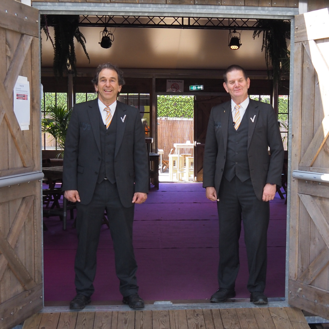 Twee evenementenbeveiligers staan voor de VIP entree van een evenement