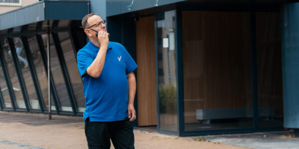 Objectbeveiliger communiceert door de portofoon terwijl hij buiten bij een gebouw staat