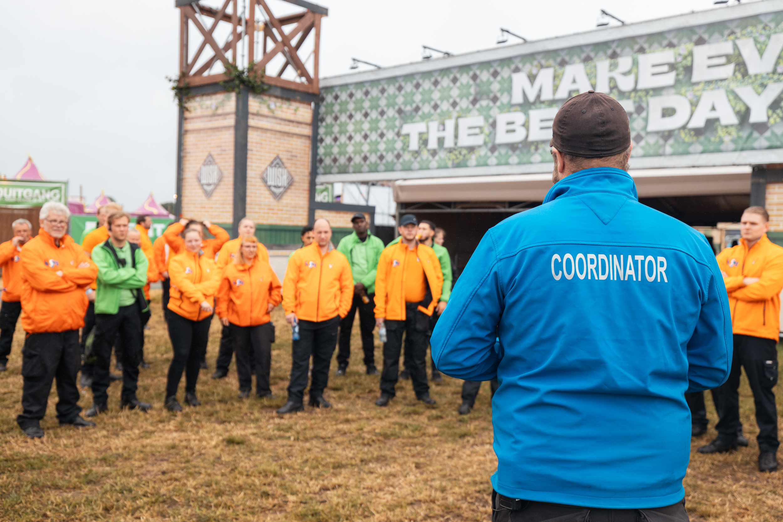 Evenementen coördinator geeft instructie aan een grote groep evenementenbeveiligers en service medewerkers